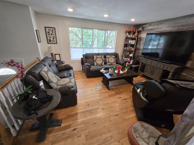 Spacious living area featuring wood-finish flooring, a prominent accent wall with horizontal paneling, and recessed lighting