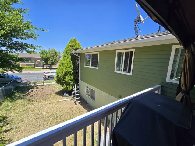 Green exterior siding with white window frames and a white deck railing