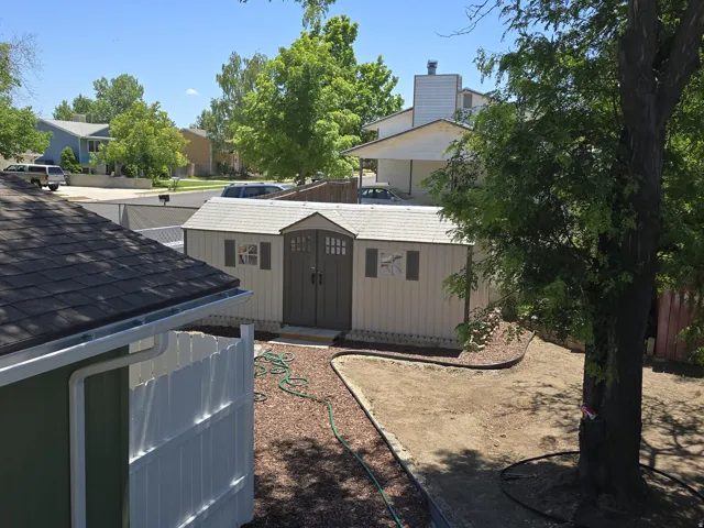 Backyard storage shed featuring double doors and two windows