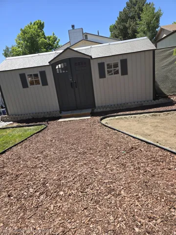 Storage shed with double doors, two windows, and dark shutters