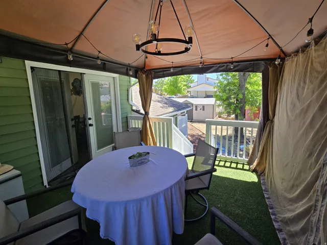 Covered outdoor deck featuring a fabric canopy, string lights, and a decorative chandelier