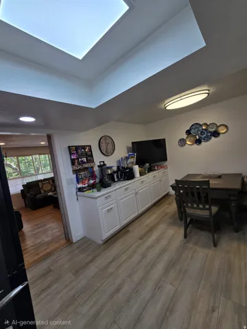 Recessed ceiling light with a large skylight, wood-finish flooring, white cabinetry with a light-colored countertop, and a built-in ceiling light fixture