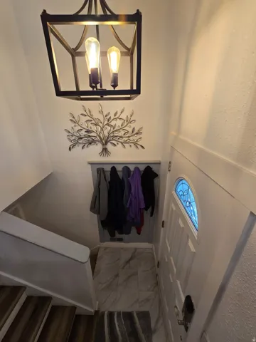 Foyer featuring a decorative lantern light fixture, wood-finish stair treads, and a front entry door with an arched stained glass inset
