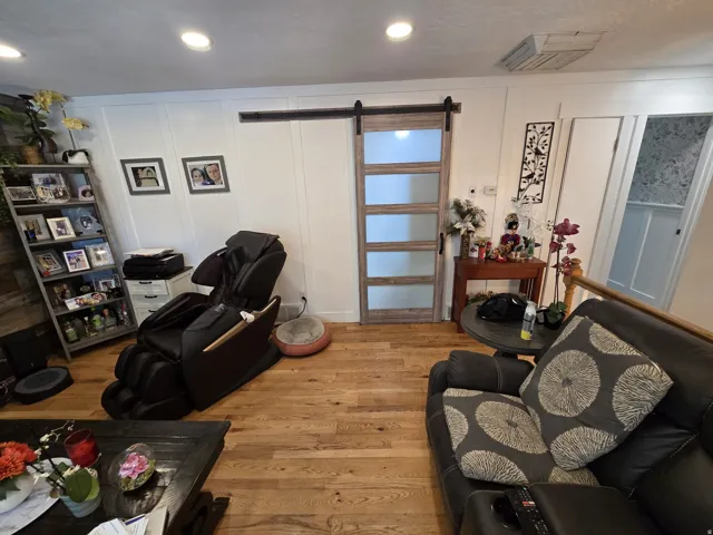 Hardwood flooring complemented by recessed lighting and a sliding barn door with frosted glass panels