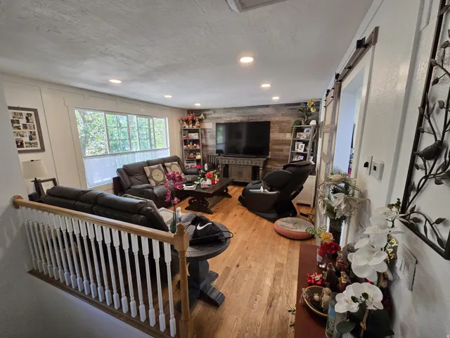 Hardwood flooring throughout featuring a decorative accent wall, recessed lighting, expansive windows, and a sliding barn door
