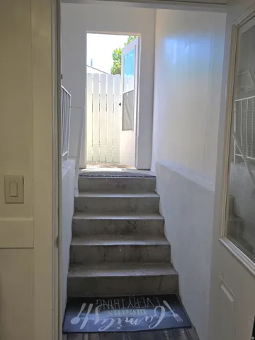 Concrete staircase with white painted walls and wood-finish flooring