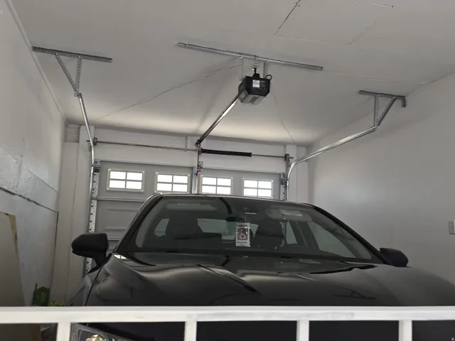 Attached garage featuring a white paneled door with upper window inserts, white painted walls, and a visible garage door opener system