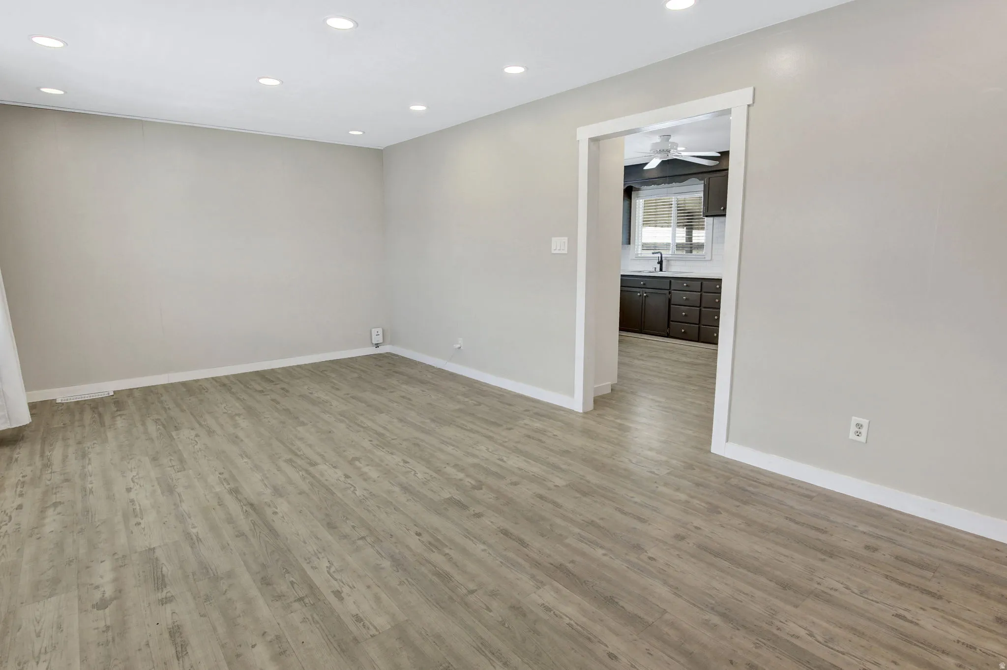 Open-concept living area with recessed lighting, light wood-finish flooring, and a neutral color palette