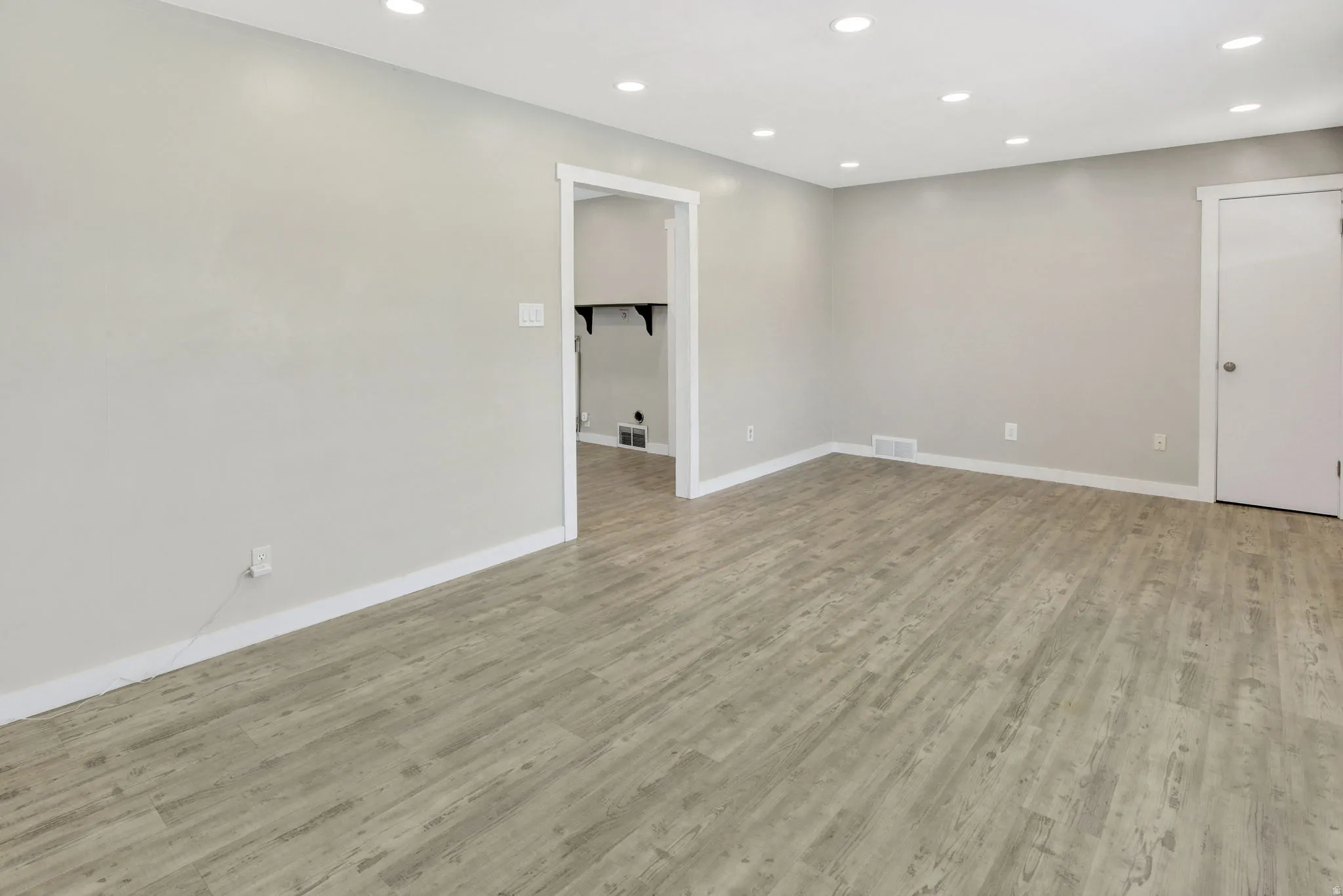 Spacious room featuring wood-finish flooring, recessed lighting, neutral paint, and white trim