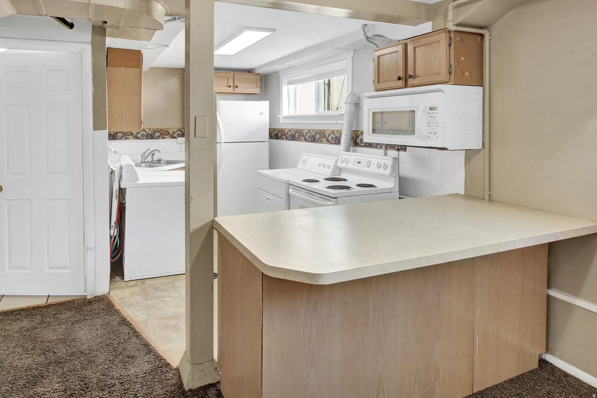 Kitchenette featuring an integrated breakfast bar, white appliances, and wood-finish cabinetry