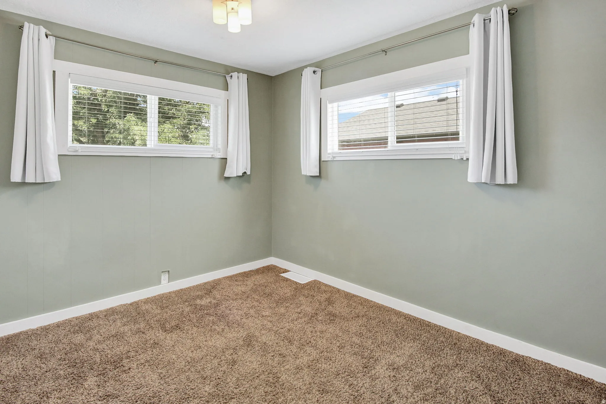 Interior room featuring two windows, neutral wall tones, and brown carpet flooring