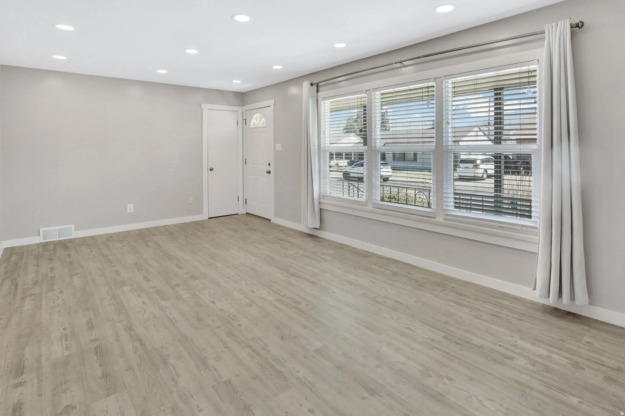 Living area featuring wood-finish flooring, recessed lighting, and a front entry door with a decorative glass insert