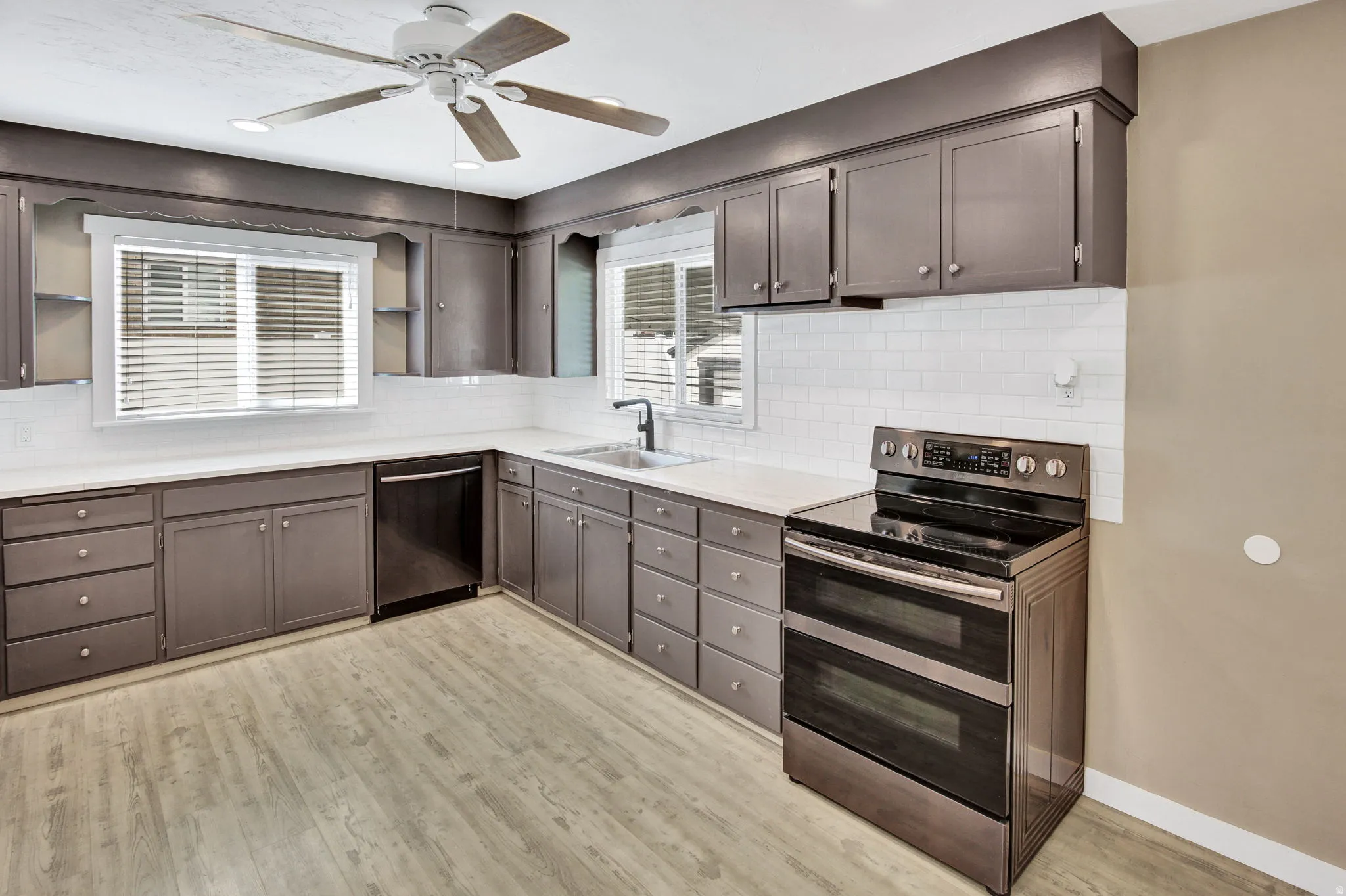 Kitchen featuring extensive cabinetry, white subway tile backsplash, stainless steel appliances, and wood-finish flooring
