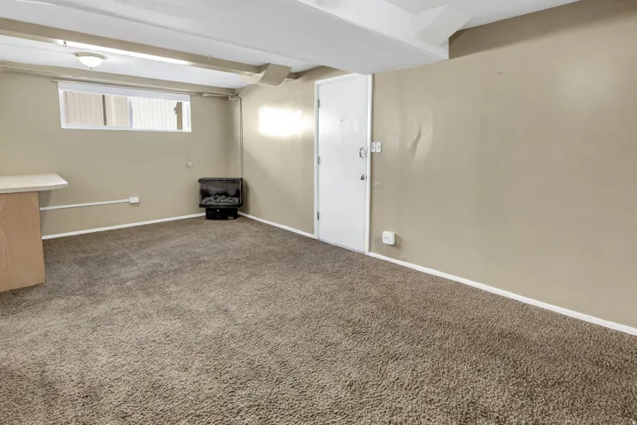 Carpeted room with a wall-mounted electric fireplace and a white door