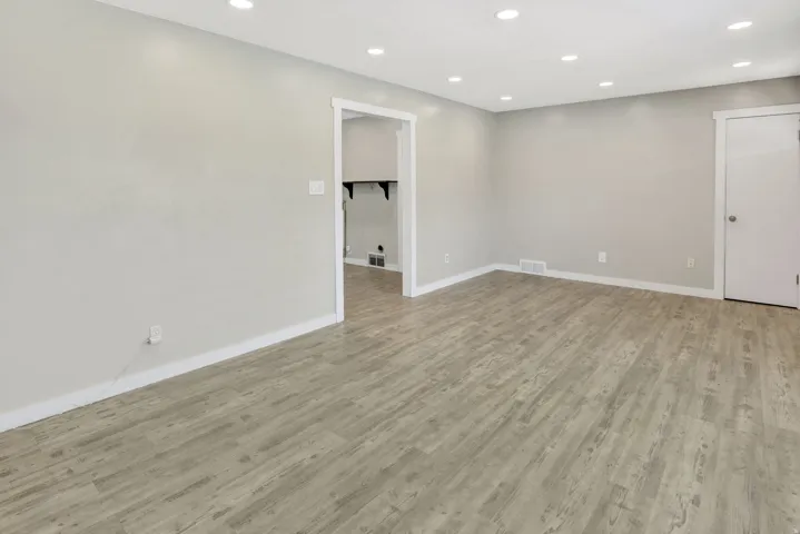 Spacious room featuring wood-finish flooring, recessed lighting, neutral paint, and white trim