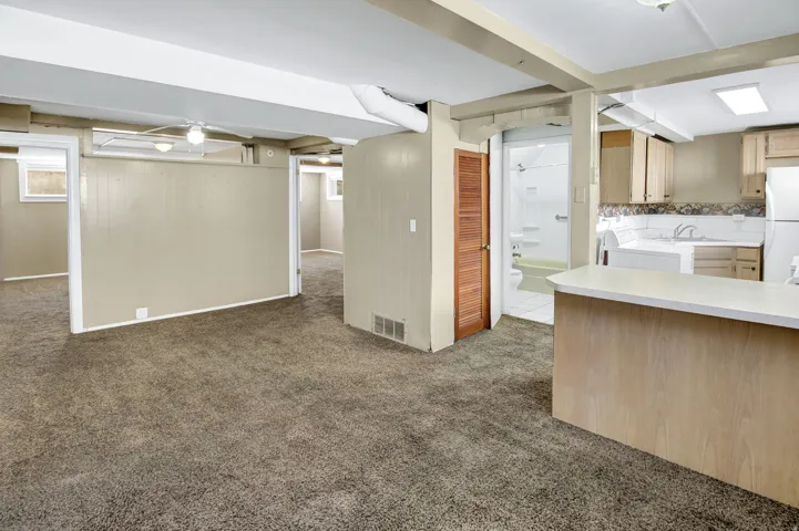 Spacious carpeted area with exposed ceiling beams and recessed lighting