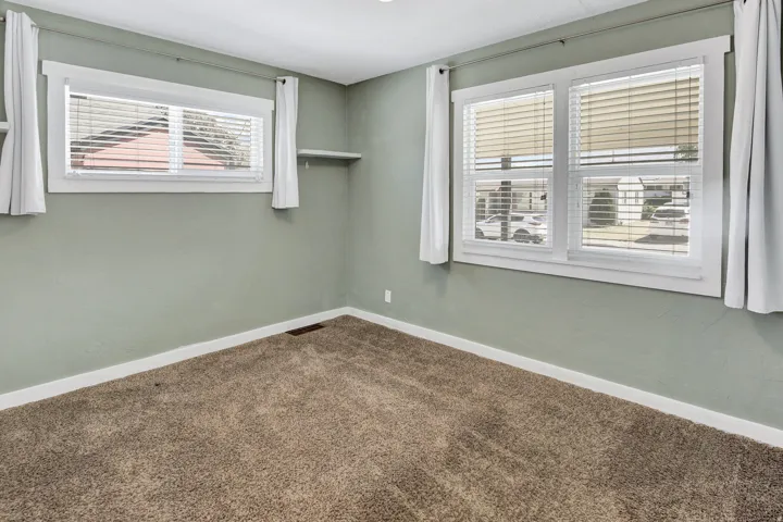 Interior space featuring wall-to-wall carpeting, light green wall finishes, white trim, and two windows with white blinds