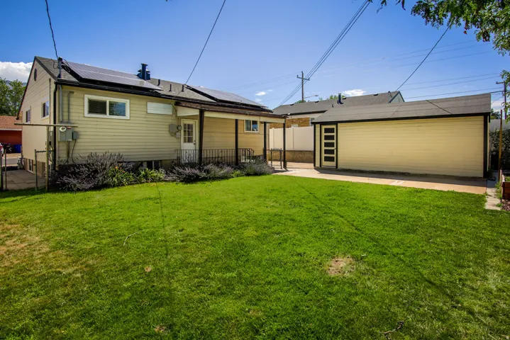 Expansive green lawn with a detached garage featuring a pedestrian door with vertical window panels