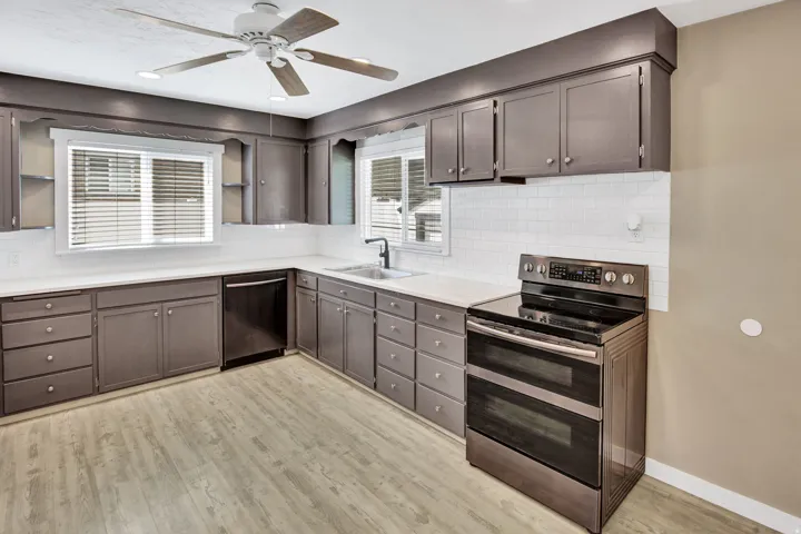 Kitchen featuring extensive cabinetry, white subway tile backsplash, stainless steel appliances, and wood-finish flooring