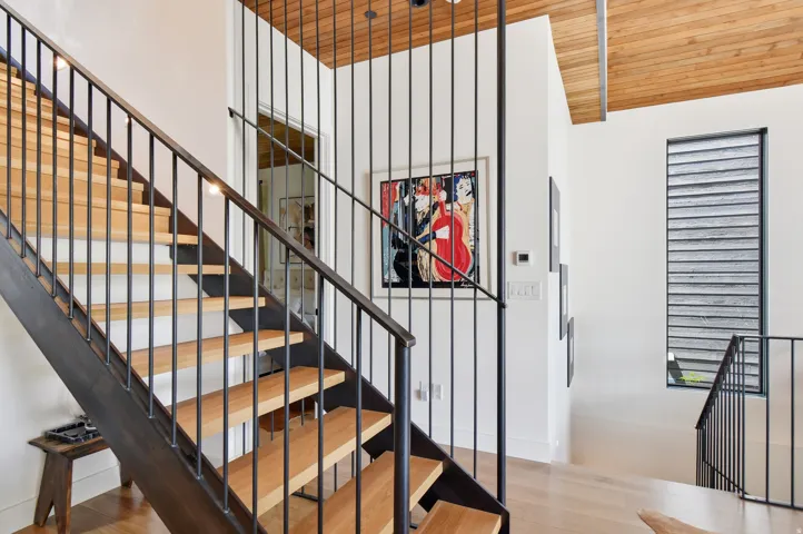 Open-tread staircase with custom metal railing and wood-finish steps