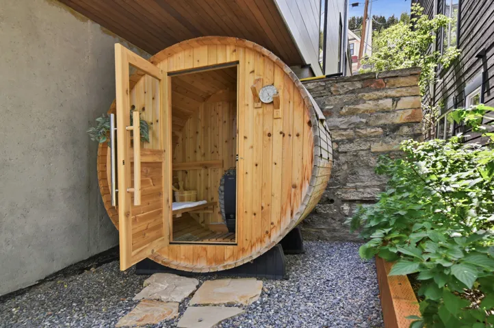 Barrel sauna featuring a clear cedar interior, built-in seating, and a stone heater