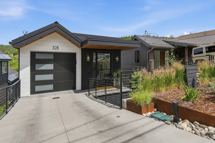 Contemporary exterior featuring black siding, white horizontal paneling, a modern garage door with rectangular windows, and a black metal roof