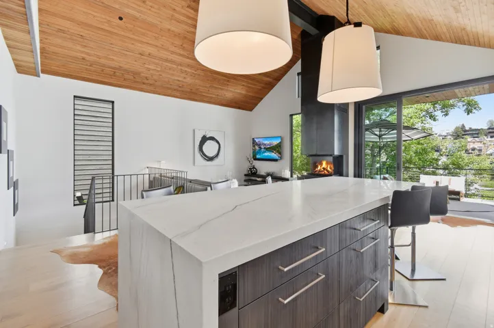 Waterfall island with a light-toned countertop, wood-finish flooring, and a vaulted wood-paneled ceiling