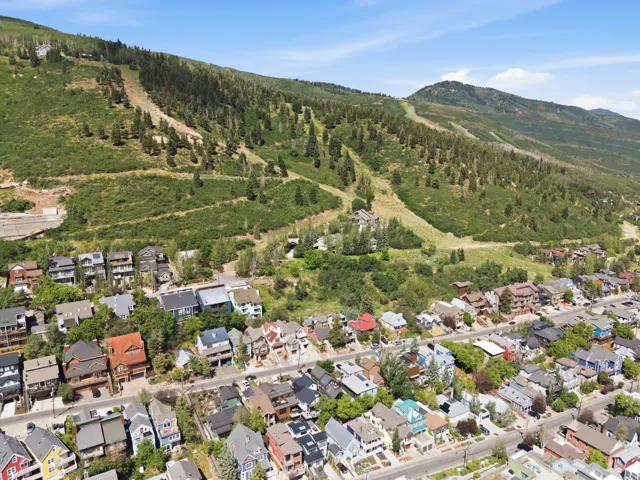 Aerial overview showcasing a mountain community with diverse architectural styles, tree-lined streets, and a prominent mountain backdrop featuring ski runs