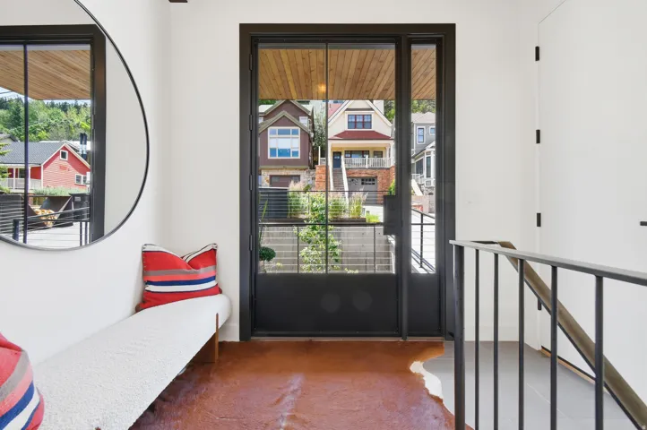 Modern entryway featuring a full-light black-framed door, wood-finish ceiling accent, polished concrete flooring, and a contemporary black metal railing