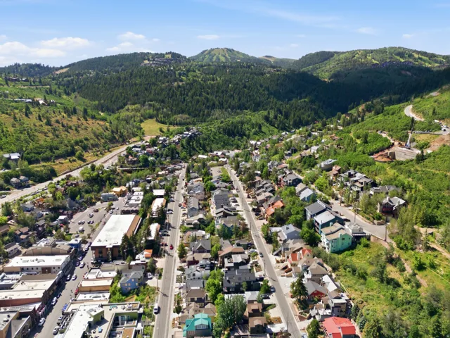 Aerial perspective of a mountainside town with residential and commercial structures nestled among lush green hills