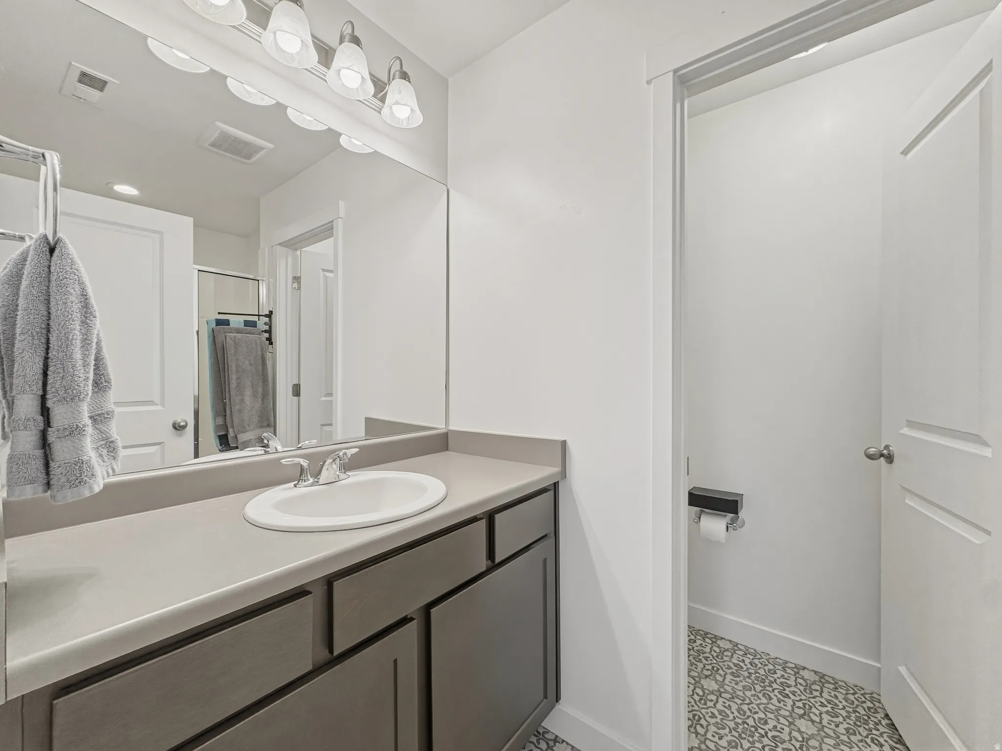 Bathroom vanity featuring a single basin sink, chrome faucet, and expansive countertop