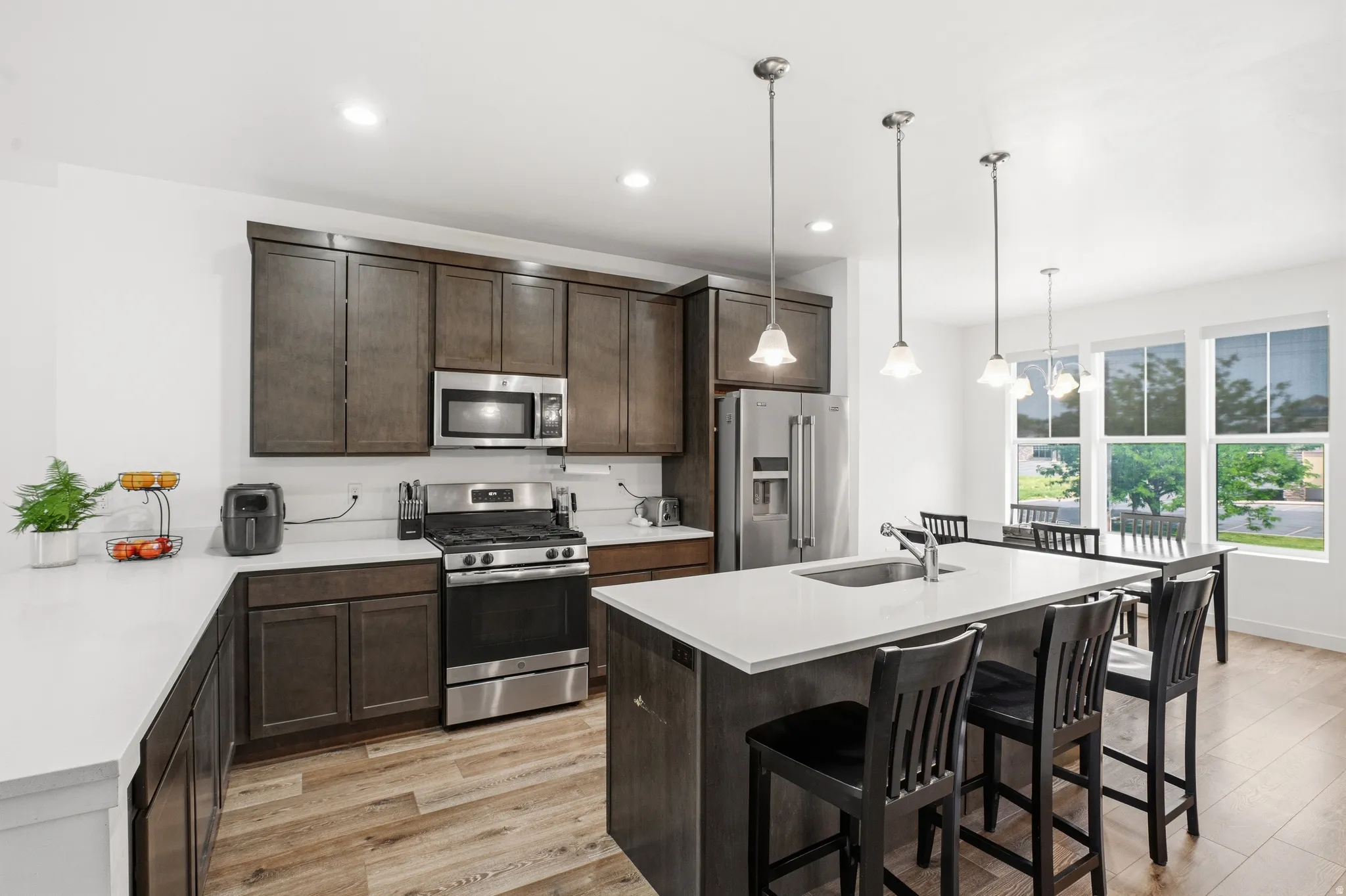 Kitchen featuring dark wood cabinetry, stainless steel appliances, light countertops, and wood-finish flooring