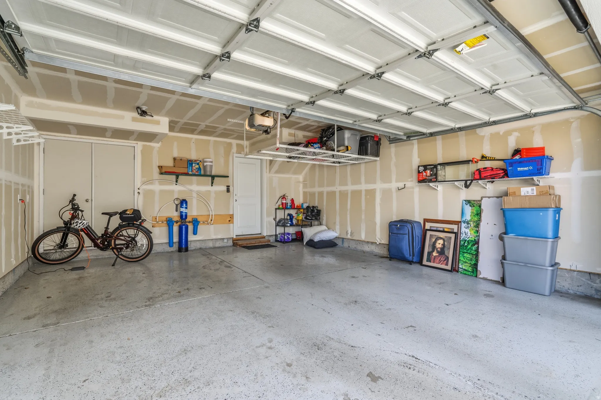 Spacious garage featuring a durable epoxy-coated floor, overhead storage racks, and built-in shelving