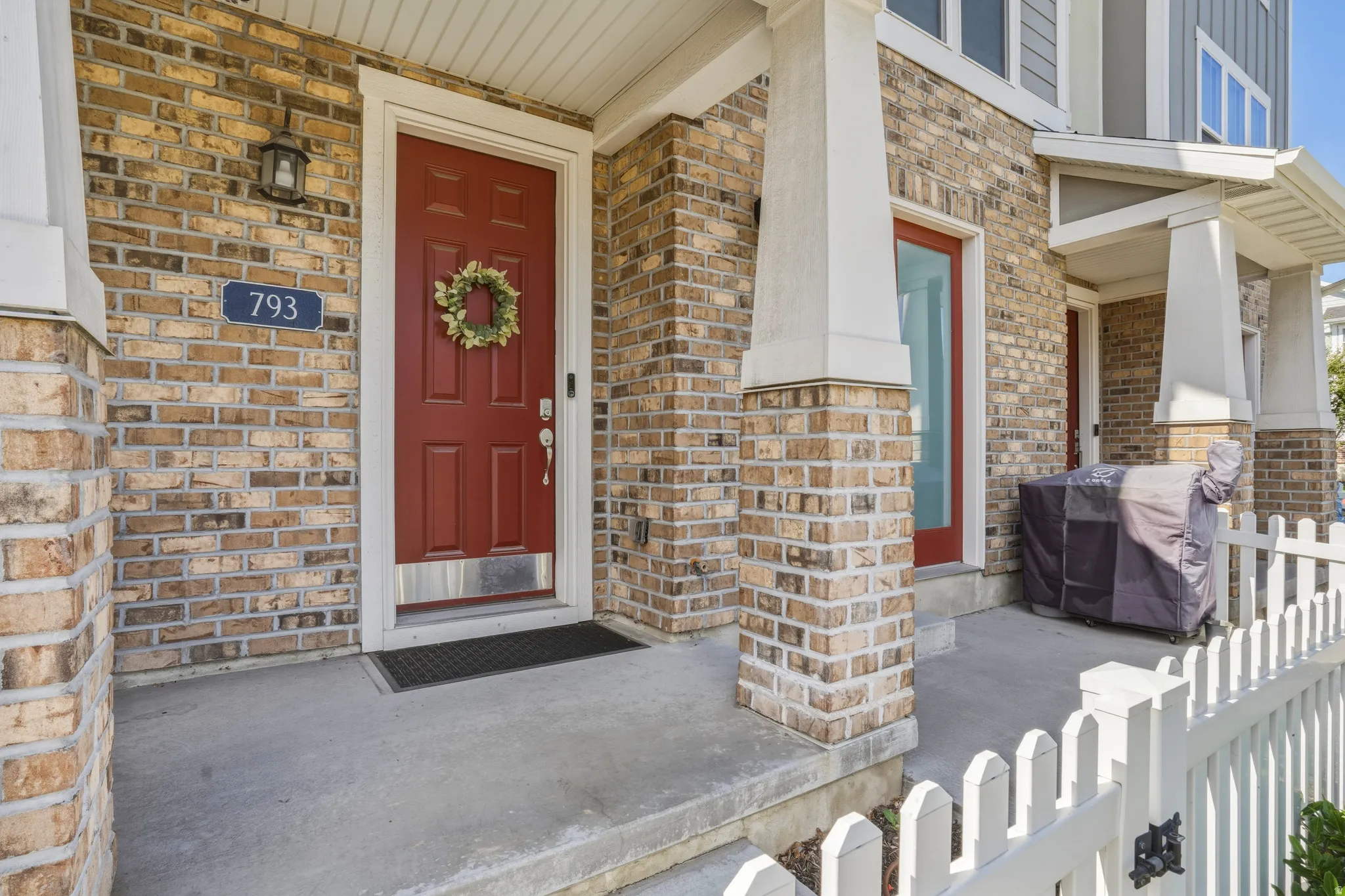 Brick facade with a vibrant red entry door featuring a transom window