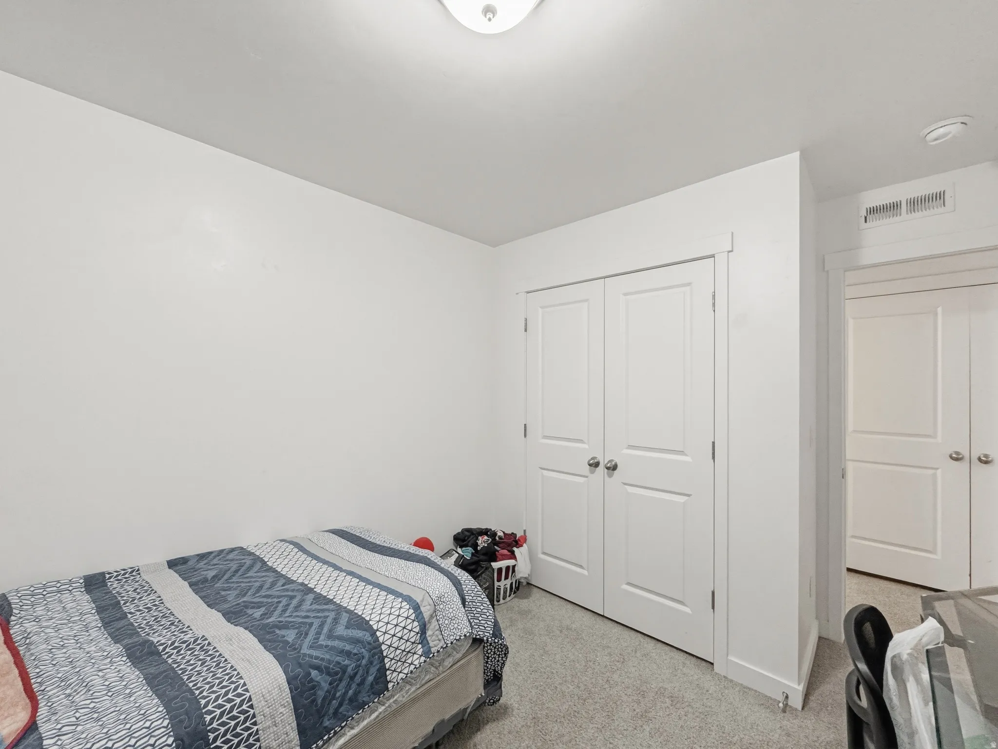 Room featuring neutral wall paint, light-colored carpet, a flush-mount ceiling light fixture, and a white bi-fold closet