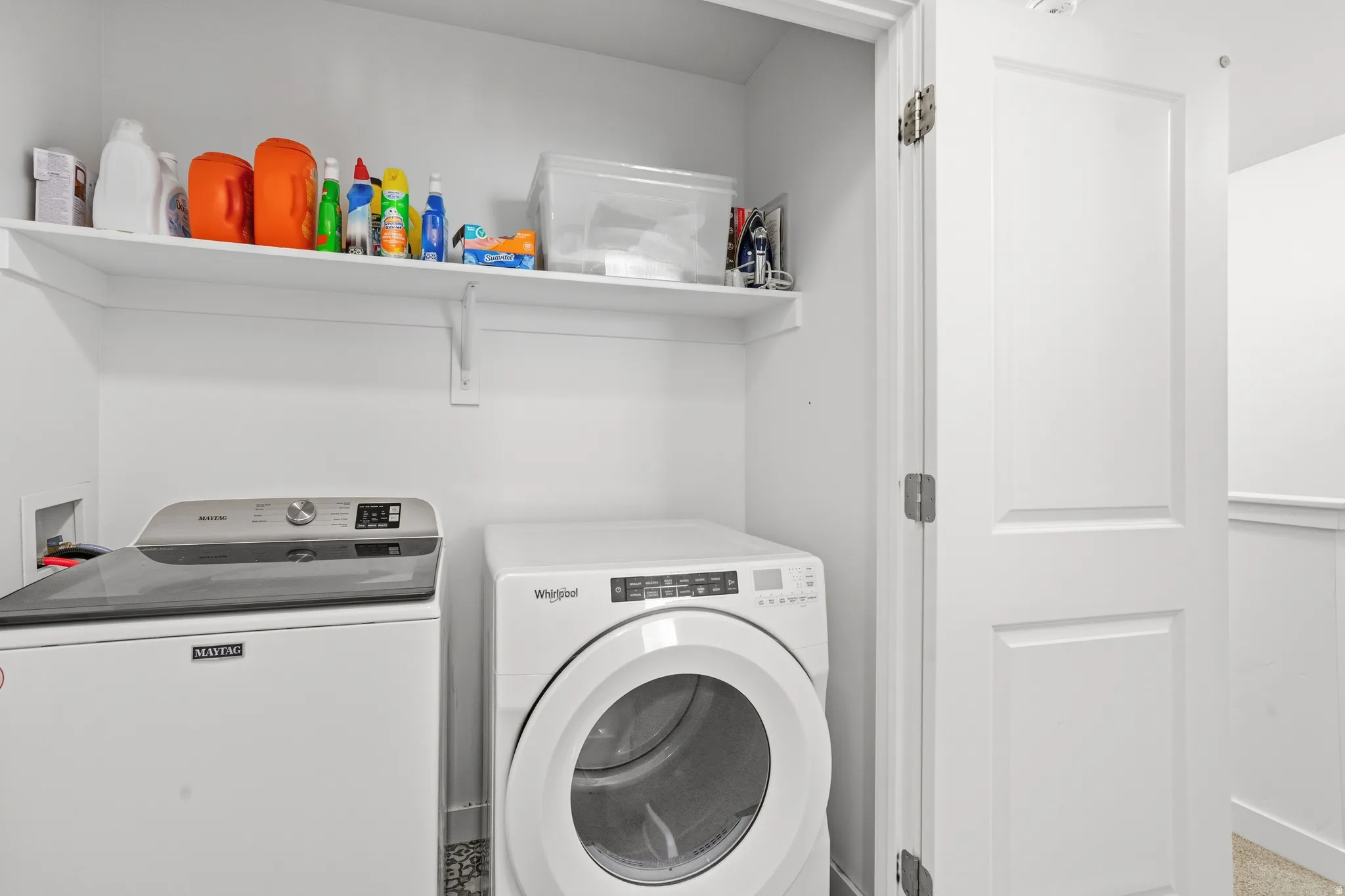 Dedicated laundry space featuring a white top-load washer, a white front-load dryer, and an overhead storage shelf