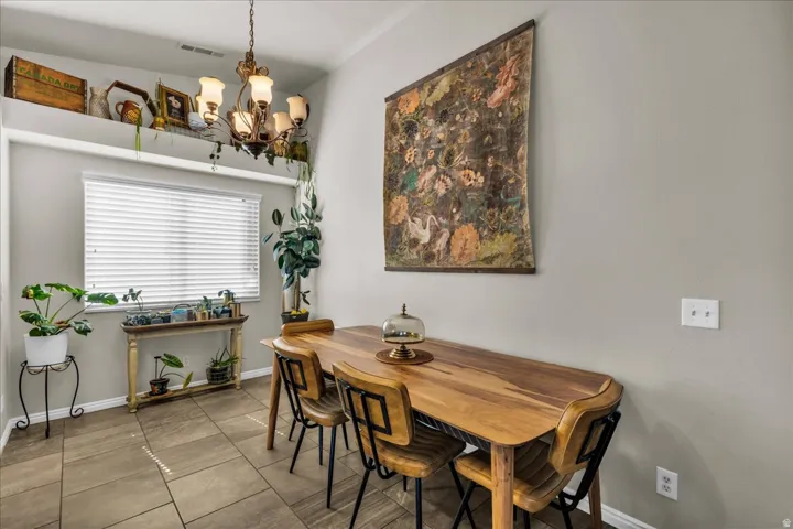 Dining area featuring a contemporary chandelier, tile flooring, and a large window with blinds