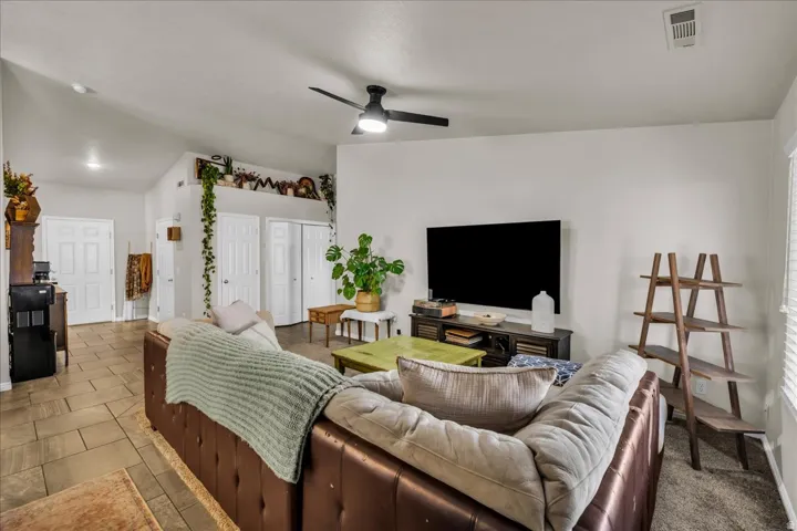 Open-concept living area featuring a vaulted ceiling and a ceiling fan