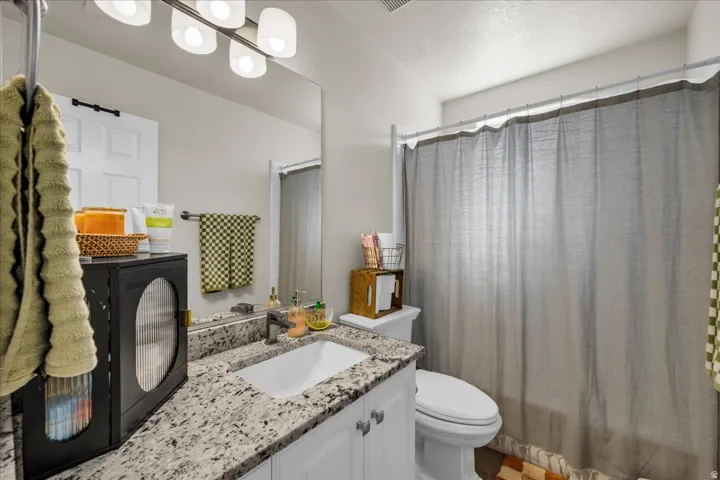 Bathroom featuring a white vanity with a speckled countertop, undermount sink, and chrome faucet