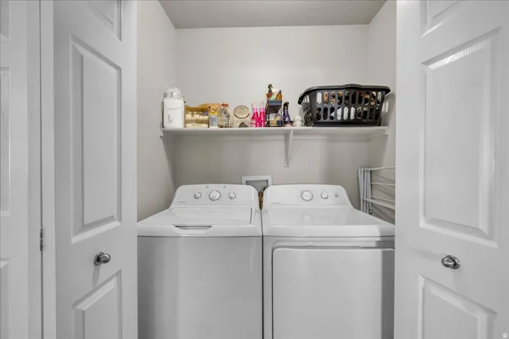 Dedicated laundry area featuring a washer and dryer, white shelving, and white paneled bi-fold doors