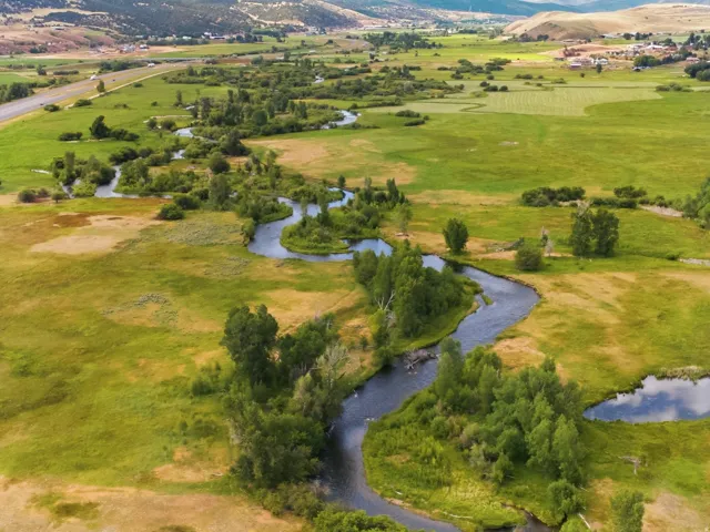 Meandering river winding through expansive green and golden fields