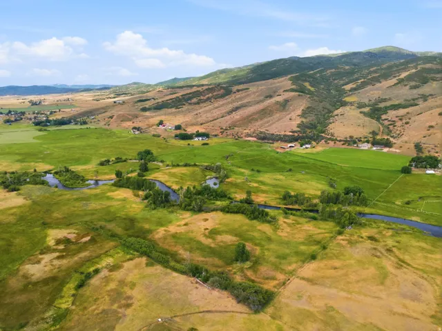 Expansive rural landscape featuring a winding river, verdant fields, and distant mountainous terrain