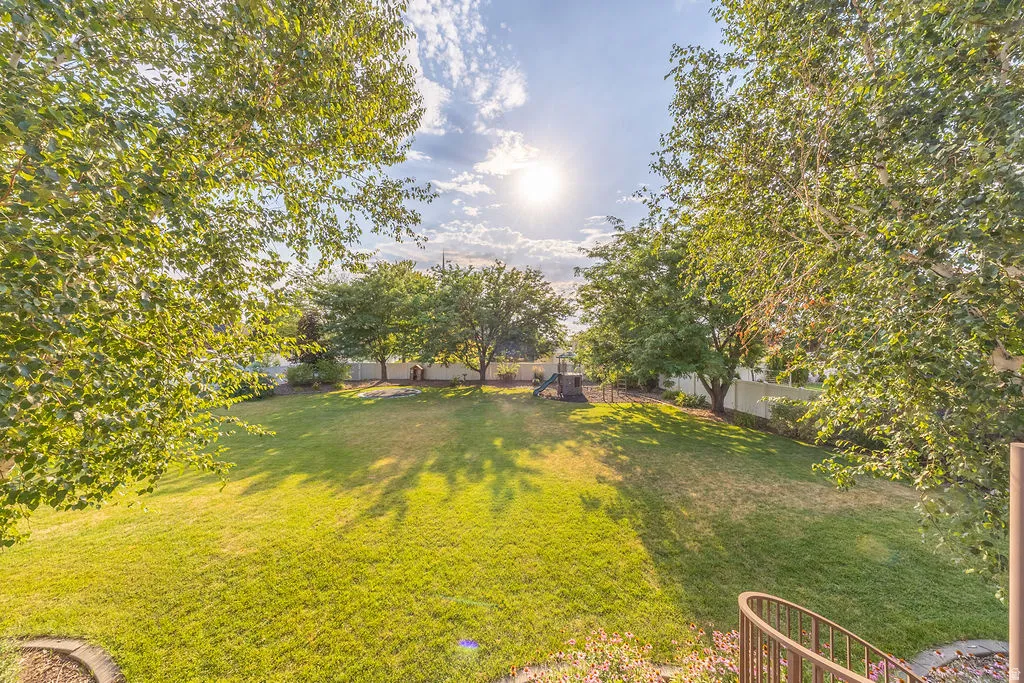 Expansive backyard featuring a large grassy lawn, mature trees, and perimeter fencing
