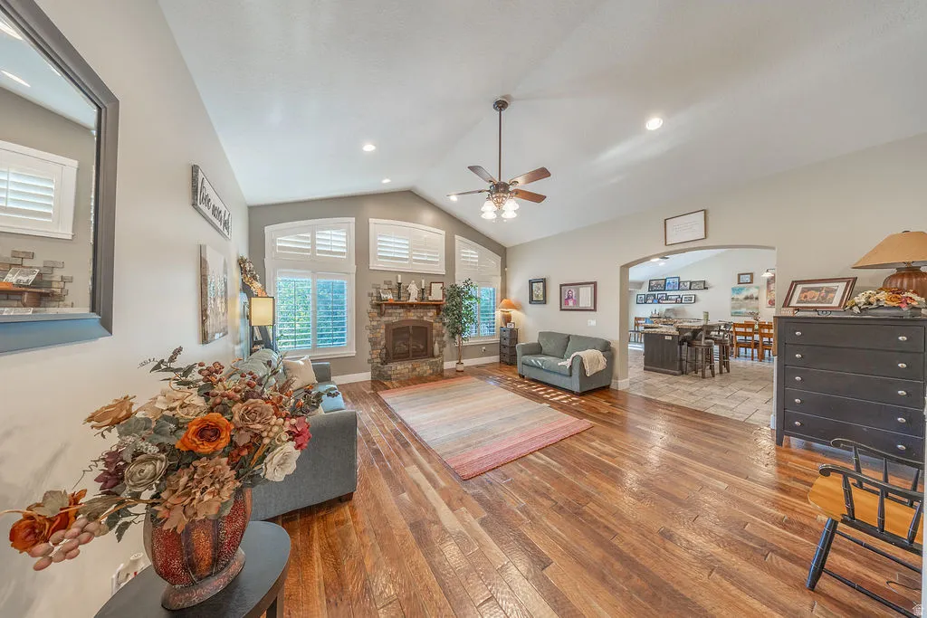 Spacious living area featuring high vaulted ceilings, rich wood-finish flooring, and a stone-faced fireplace