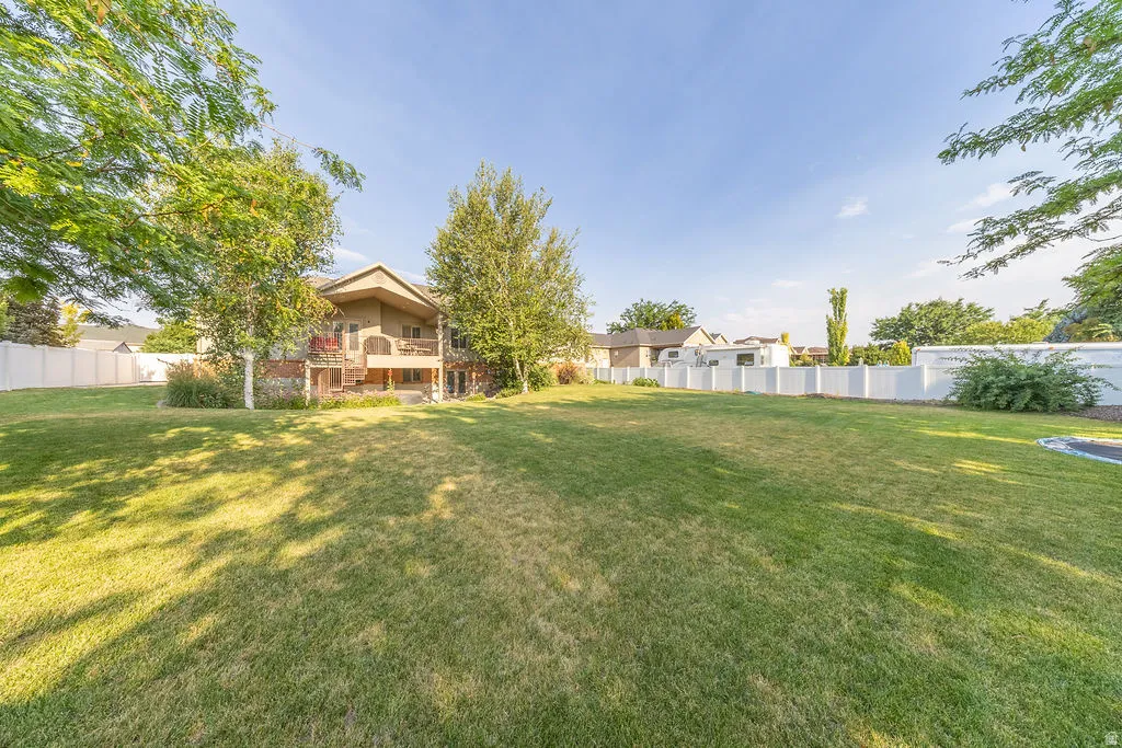 Expansive fenced backyard featuring a large green lawn and mature trees