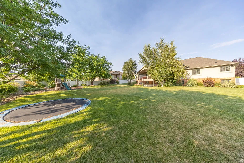 Expansive lawn area featuring mature trees and a perimeter fence