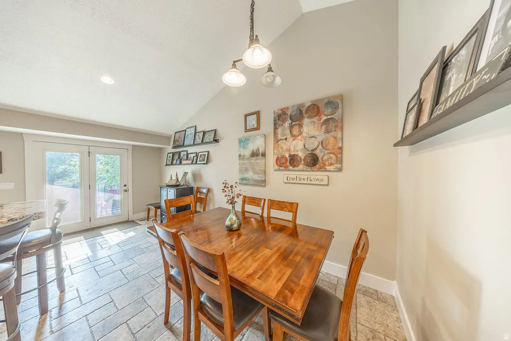 Vaulted ceiling dining area featuring tile flooring, white double French doors, and recessed lighting