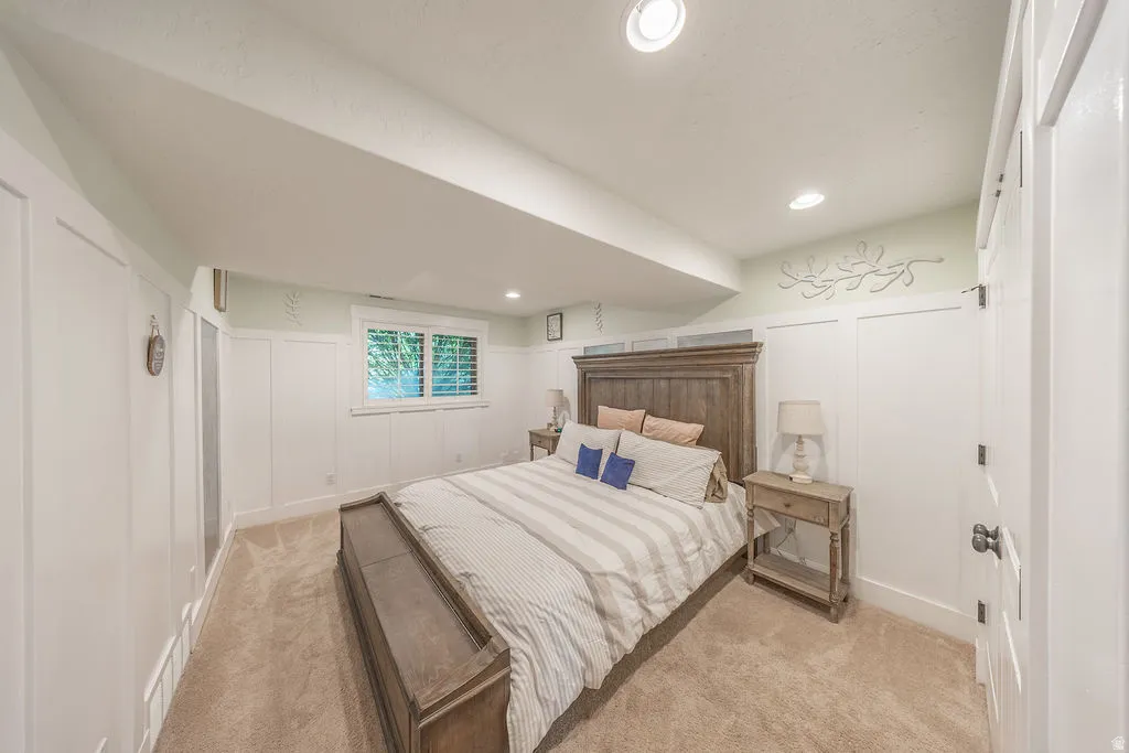Bedroom featuring board and batten wainscoting, recessed lighting, and a window with plantation shutters