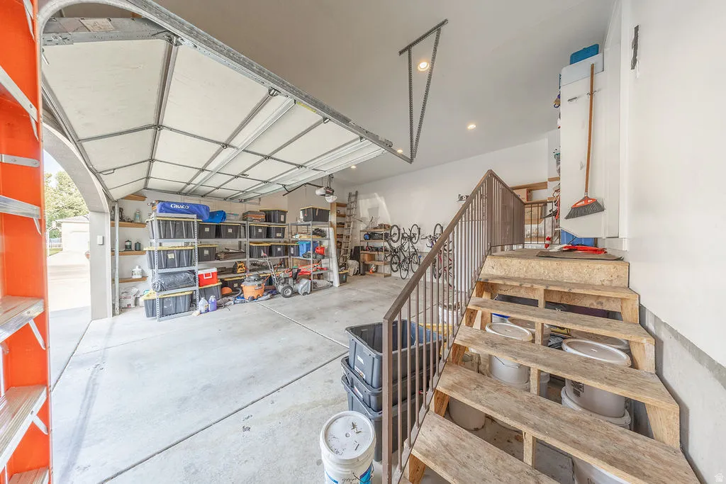 Attached two-car garage with a concrete floor, overhead lighting, and built-in shelving