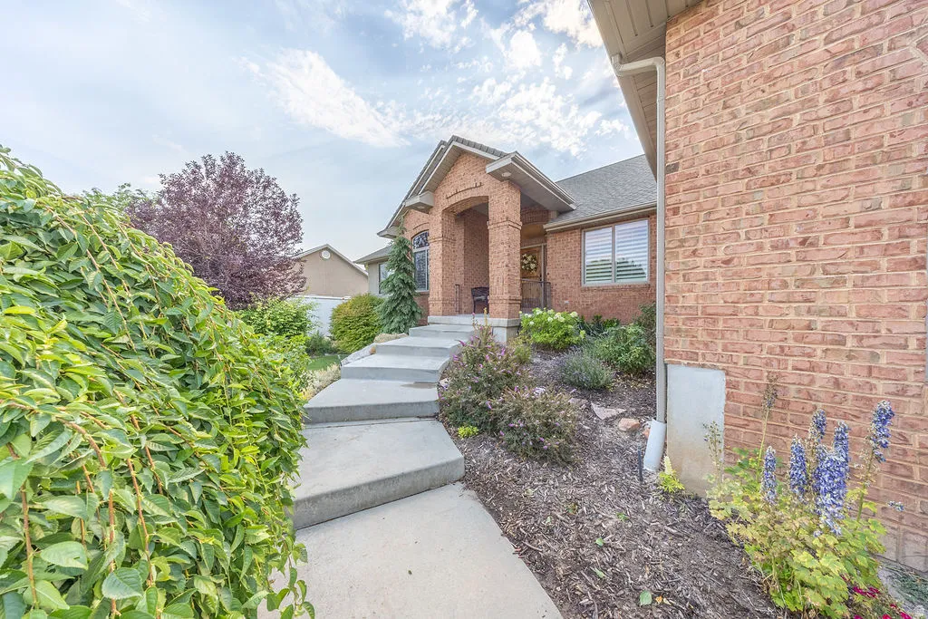 Brick exterior featuring an arched entryway, covered porch, and stepped concrete walkway